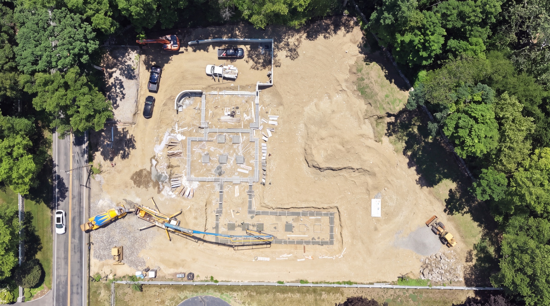 Aerial view of poured concrete footings and a pump truck placing foundation concrete.