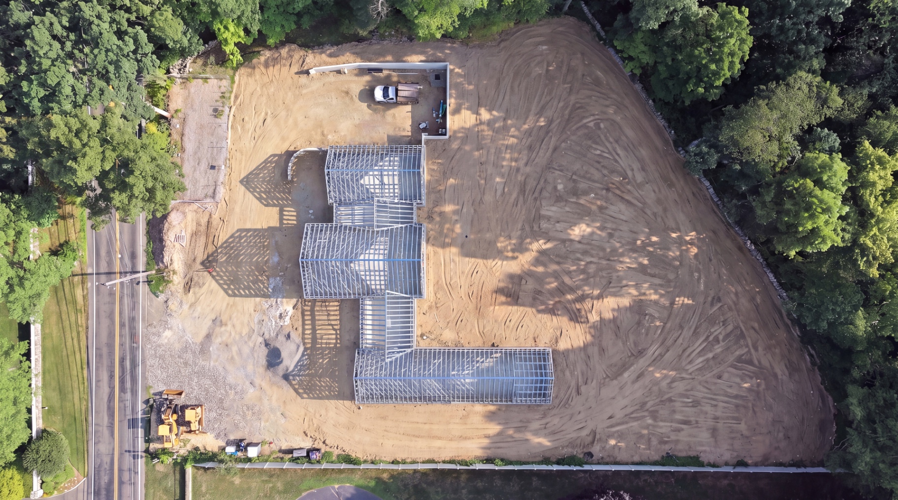 Aerial view of the metal framing skeleton rising on the completed foundation.